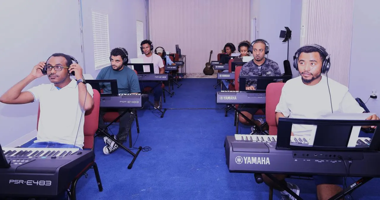 A wide view of the keyboard classroom, students seated at their keyboards